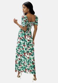 Robe maxi florale avec des motifs verts et bordeaux sur fond blanc, dotée de manches ballon et d'un corsage à smocks. Texture de tissu lisse.