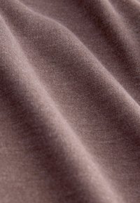 Tissu marron avec une texture lisse, présentant des motifs en tricot fins et une apparence douce, agencé en plis et courbes délicates.
