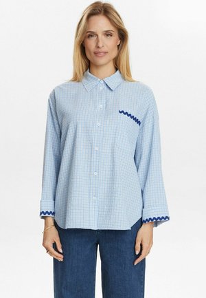 Blaue karierte Hemd mit spitzem Kragen, Knopfleiste und marineblauem gewellten Besatz an den Ärmeln und der Brusttasche. Hergestellt aus leichtem Stoff.