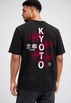 Man wearing black T-shirt with red floral design and white text reading "Kyoto," Japanese characters, and "Japan" on the back.