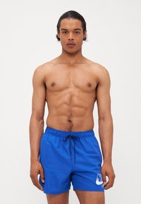 Shorts de bain bleus en tissu léger, dotés d'une taille élastique, d'un cordon de serrage et d'un logo blanc sur le côté gauche.