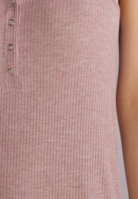 Jasnoróżowy, rypsowy top na ramiączkach o fasonie henley, z trzema metalowymi guzikami pośrodku oraz miękką bawełnianą fakturą.