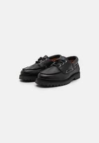 Black leather shoes with a rounded toe, lace-up front, metal eyelets, and a textured rubber sole for traction. Accented with stitching details.