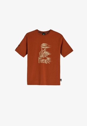 Bawełniany t-shirt w kolorze rdzy z krótkim rękawem. Z przodu znajduje się kremowy nadruk graficzny w postaci abstrakcyjnych kształtów oraz słowo "DAKAR".