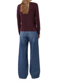 Bordeaux langemouwtop met een ronde hals, gedragen met een wijdvallende spijkerbroek in blauw, met een klassieke vijf-pocket ontwerp en een medium was.