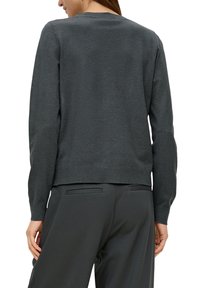 Dunkelgrauer Pullover mit langen Ärmeln, Rundhalsausschnitt und glatter Textur; getragen mit grauen Hosen, die ein schlichtes, tailliertes Design zeigen.
