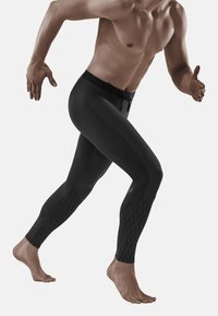 Zwarte sportleggings gemaakt van een gladde, rekbare stof, met een geprofileerd ruitpatroon op de onderbenen en een verstelbare tailleband.