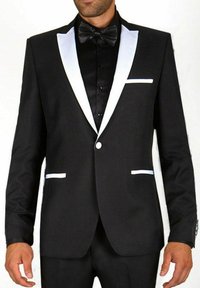 Veste de smoking noire avec des revers en satin blanc, une fermeture à un bouton et des accents de poche blancs. Stylée avec un nœud papillon noir et une chemise.