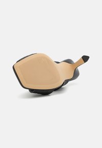 Semelle de chaussure à talon haut noire avec une base lisse couleur tan ; présente une texture ribbée et un bout pointu. Design simple sans marque visible.