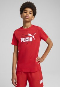 Camiseta de algodón roja con un estampado gráfico blanco que incluye el texto y el logo de "PUMA". Mangas cortas y un diseño clásico de cuello redondo.