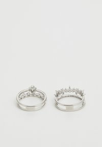 To sølvringer: den ene har en glatt ring, mens den andre har en dekorativ kroneform med steindekor og intrikate detaljer.