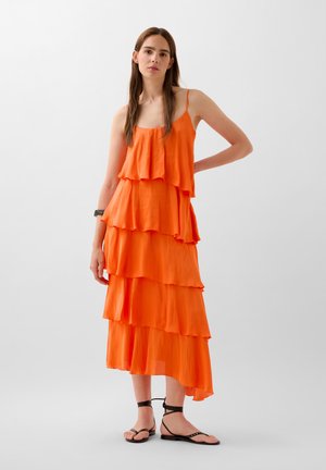 Rochie midi portocalie, cu volane in straturi, cu bretele subtiri, realizată dintr-un material ușor. Prezintă volane suprapuse, o croială lejeră și un tiv înalt și jos.
