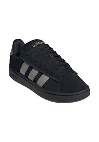 Schwarzer Adidas Sneaker mit grauen Streifen, schwarzen Schnürsenkeln und Logo auf Zunge und Sohle, nach rechts geneigt auf weißem Hintergrund.