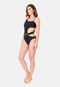 Costume da bagno intero nero con fianchi tagliati, spalline regolabili e un accento circolare in vita. Realizzato in tessuto liscio e elasticizzato.