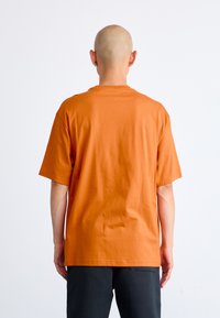 Kortærmet orange t-shirt lavet af bomuld, med en afslappet pasform og rund halsudskæring, samt en glat overflade. Enkel design uden mønstre.