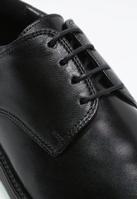 Black leather dress shoe with a smooth finish, round toe, and traditional lace-up design featuring six eyelets and structured stitching details.