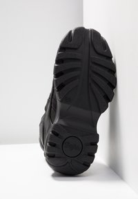 Black boot sole with deep treads, "Buffalo" logo at heel, size 37 marking, positioned upright against white cornered walls.