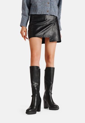 Stivali neri in pelle alti fino al ginocchio con tacco a blocco, dotati di una cerniera laterale e di una fascia alla caviglia. Texture liscia e design elegante.