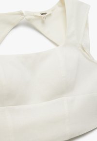 Witte crop top gemaakt van een gladde stof. Heeft een brede halslijn en schone, gestructureerde lijnen met minimale stikseldetails.