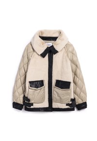 Veste beige et noire présentant un matériau doux, similaire à de la fourrure sur le corps, des manches matelassées et rembourrées, ainsi que de grandes poches en faux cuir noir.