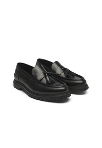 Mocassins noirs en cuir, avec un design de mocassin, ornés d'un accent à franges et d'une semelle en caoutchouc épaisse pour une meilleure traction. Texture lisse.