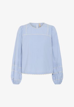 Svetlo modra bluzica s krožnim ovratnikom, napihnjenimi dolgimi rokavi in belim valovitim obrobo na yoku in manšetah. Zruhe je teksturirano detajliranje.