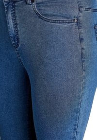 Jeans de mezclilla azul oscuro con una textura suave, que cuentan con un diseño clásico de cinco bolsillos y costuras en contraste a lo largo de las costuras.