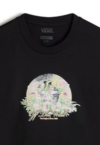 Camiseta de algodón negra con un gráfico colorido de dos pájaros y flores sobre un fondo circular con el texto "Off The Wall".