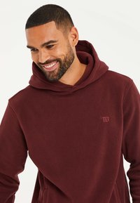 Burgundy Kapuzenpullover aus Fleece mit einer Vordertasche, ausgestattet mit einem dezenten, in passender Farbe gestickten "TB"-Logo.
