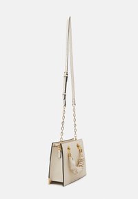 Cremefarbene rechteckige Handtasche mit gerafftem Griff, goldfarbenen Kettenriemen und verstellbarem Schulterriemen vor weißem Hintergrund.