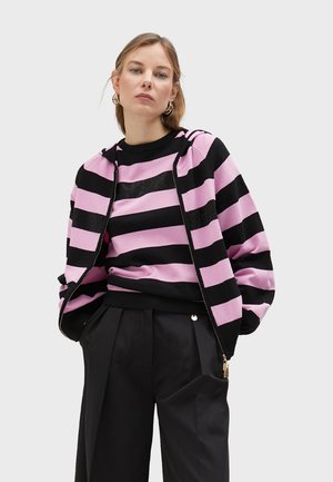 Black and pink striped sweatshirt with a zip-up design, featuring a round neck and textured accents, paired with black pleated trousers.