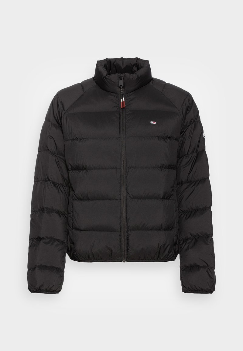 Doudoune matelassée noire avec fermeture éclair intégrale à l'avant et col montant, avec un petit logo rouge, blanc et bleu sur la poitrine et la manche gauche.
