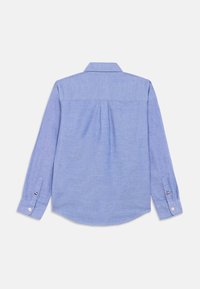 Lyseblå langermet skjorte som ligger flatt med baksiden opp, med knappede mansjetter og en sentrert plissè under skulderpartiet.