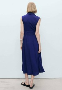 Abito senza maniche blu navy con colletto, vita aderente e gonna fluida; tessuto strutturato e lunghezza fino al polpaccio. Design minimalista.