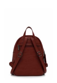 Sac à dos en cuir rouge avec deux bretelles réglables, une poignée supérieure et une poche zippée à l'avant. Texture lisse, forme arrondie et design minimaliste.