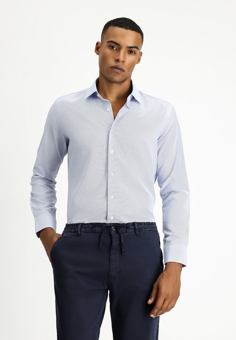 Camicia button-up azzurro chiaro in un tessuto testurizzato, con colletto e maniche lunghe, abbinata a pantaloni blu scuro con cordoncino.