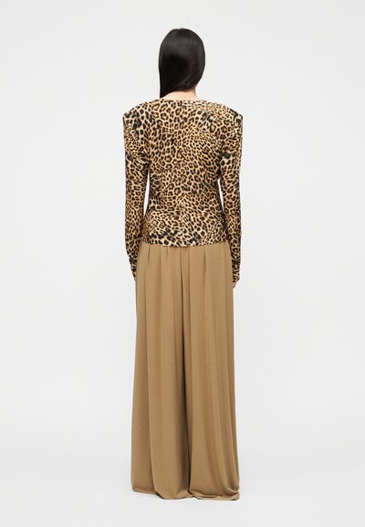 Μπλούζα με λεοπάρ τύπωμα και μακριά μανίκια με δομημένους ώμους, συνδυασμένη με μια αέρινη μπεζ maxi φούστα που αναδεικνύει ομαλή υφή υφάσματος και άνετη εφαρμογή.
