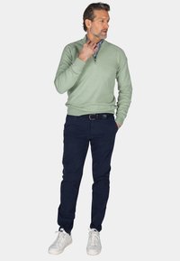 Lichtgroene, langarmpullover met een ritssluiting in de hals, gecombineerd met marineblauwe broek en witte sneakers. Textuurstof met een casual pasvorm.