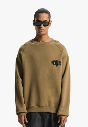 Brauner Sweatshirt mit Rundhalsausschnitt und Raglanärmeln, mit schwarzem Text auf der Brust. Der Stoff sieht weich aus und hat eine strukturierte Oberfläche.