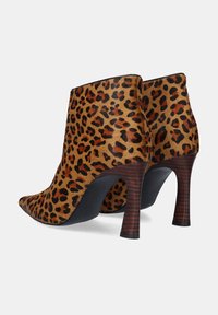 Botas de tobillo con estampado de leopardo y puntera afilada, hechas de material texturizado color marrón, presentan una suela negra brillante y un tacón de diseño tipo madera.