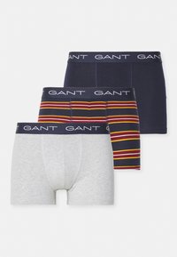 Drei Paar GANT Boxershorts: eine graue, eine marineblaue und eine gestreifte in marineblau, rot und gelb. Sie verfügen über einen elastischen Bund mit Logo.