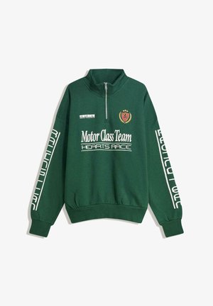 Zeleni pulover s četrtinskim zadrgo, s tekstom "Motor Class Team Hearts Race", belimi napisi na rokavih ter rdečim in zlatim vezenim grbom na prsih.