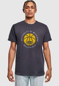 Mørkegrå bomulds t-shirt med et gult basketball-graphic og teksten "University of Michigan Wolverines" i hvidt omkring det.