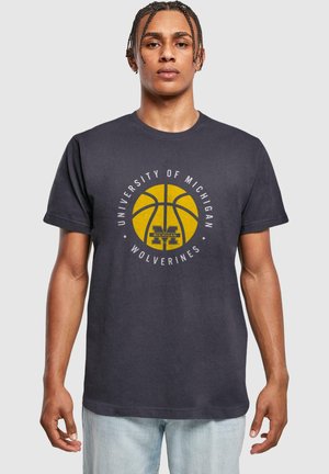 Tmavě šedé bavlněné tričko s žlutou grafikou basketbalového míče a textem "University of Michigan Wolverines" v bílé barvě okolo něj.