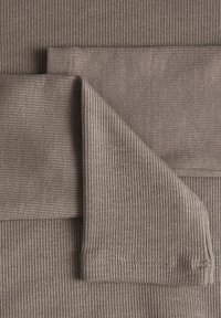 Rybkowana tkanina w jasnobrązowych odcieniach, z pionowymi paskami i gładką fakturą. Warstwy wykazują różne szerokości prążków i staranne szycie.