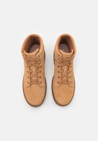Baskets montantes en daim tan avec bout rond, œillets en métal et lacets plats. Texture douce, col rembourré et semelle en caoutchouc.