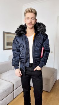 Jacket bomber azul-marinho com capuz forrado a pêlo, bolsos com fecho éclair e forro laranja. Apresenta um tecido texturizado e um pequeno emblema no peito.