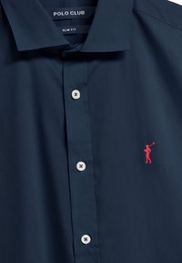Camicia slim-fit blu navy con bottoni bianchi e logo di un golfista ricamato di rosso sul petto sinistro. Tessuto morbido e liscio.