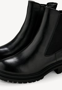 Botas de tobillo de cuero negro con un acabado suave, paneles elásticos laterales y suelas de goma resistentes. Presentan un diseño elegante y aerodinámico.