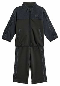 Černý teplákový komplet vyrobený z fleecu a polyesteru. Sestává z bundy na zip s vzorovanými rukávy a kalhot elastickým pasem. Ozdobený logem.